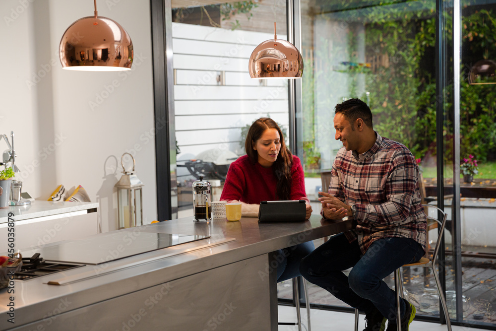 Couple financial planning at digital tablet in kitchen Couple financial planning at digital tablet in kitchen