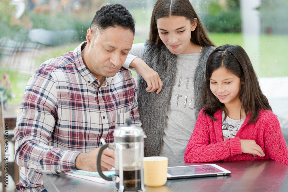 Father and daughters using digital tablet in morning kitchen Father and daughters using digital tablet in morning kitchen