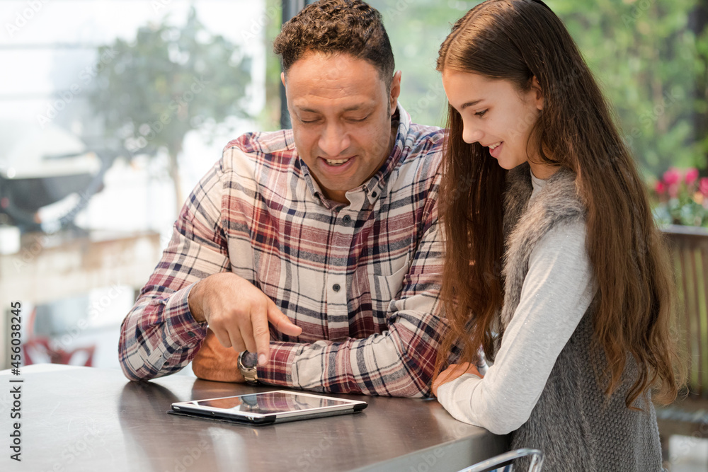 Smiling father and daughter using digital tablet at kitchen counter Smiling father and daughter using digital tablet at kitchen counter