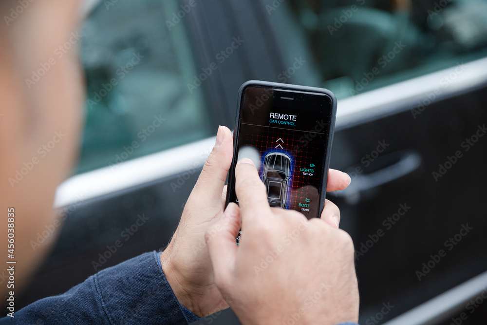 Man setting car alarm from smart phone in driveway Man setting car alarm from smart phone in driveway