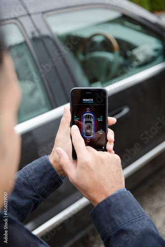 Man setting car alarm from smart phone in driveway