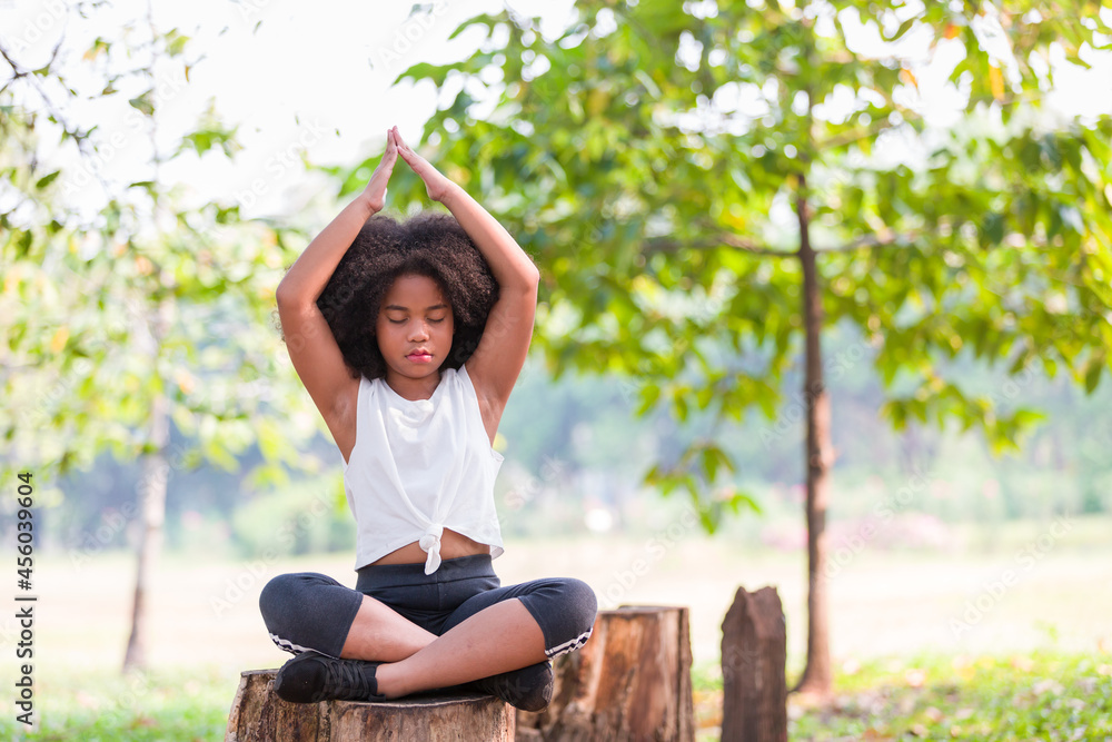 African American little girl doing meditate yoga asana with eyes closed outdoor in park. Kids girl practicing doing yoga outdoor African American little girl doing meditate yoga asana with eyes closed outdoor in park. Kids girl practicing doing yoga outdoor