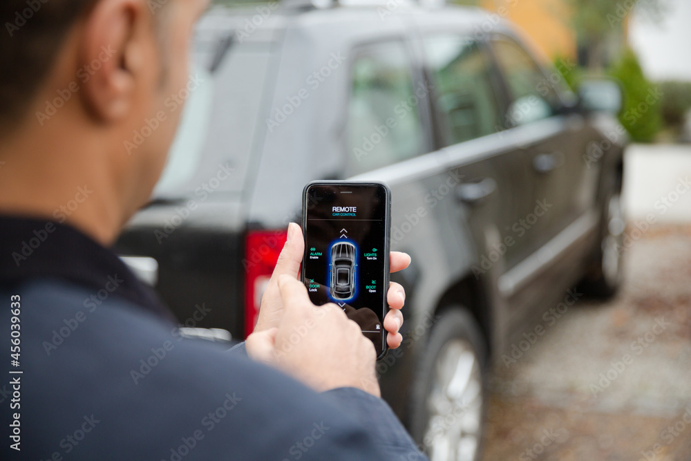Man setting car alarm from smart phone in driveway Man setting car alarm from smart phone in driveway