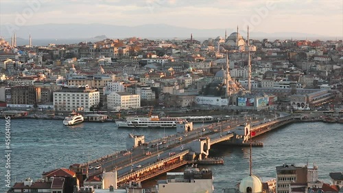 View of the Galata bridge and mosques at sunset. A lot of seagulls are flying, tourist boats are floating