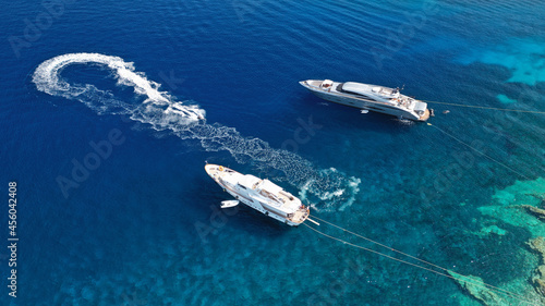 Aerial drone photo of large yachts anchored in tropical exotic paradise bay with turquoise open ocean calm sea
