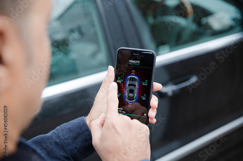 Man setting car alarm from smart phone in driveway