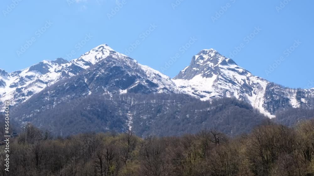 picturesque landscape of snow-capped mountains with white clouds on a blue sky on a sunny day at Krasnaya Polyana in Sochi, Russia picturesque landscape of snow-capped mountains with white clouds on a blue sky on a sunny day at Krasnaya Polyana in Sochi, Russia