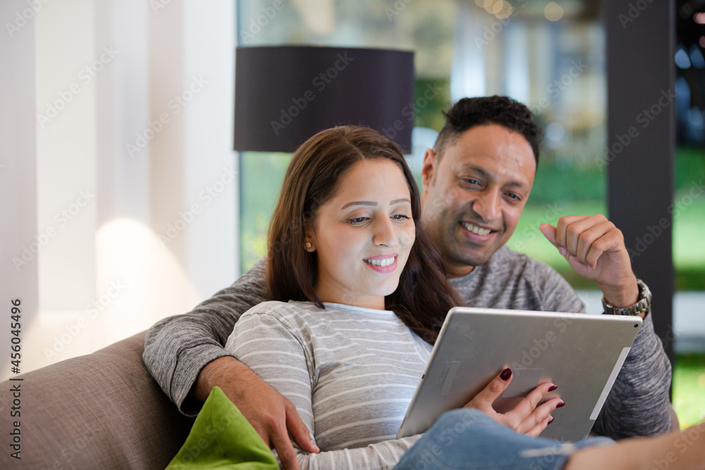 Couple relaxing, using digital tablet on living room sofa Couple relaxing, using digital tablet on living room sofa