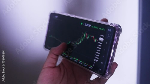 Woman Holding Phone In Landscape Mode Checking XRP's Hourly Chart photo