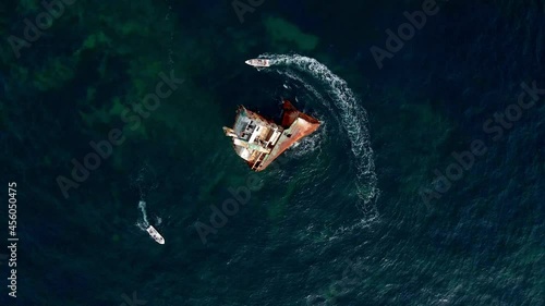 sunken ship stranded near the shore and boats are floating