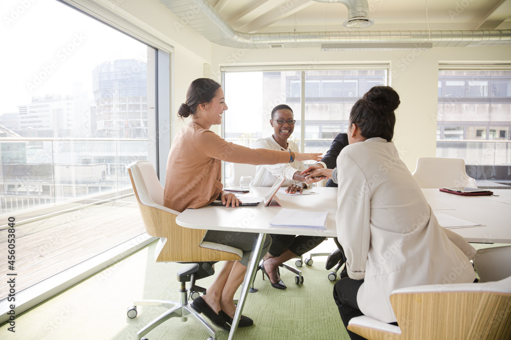 Happy business people touching hands, celebrating success in conference room Happy business people touching hands, celebrating success in conference room