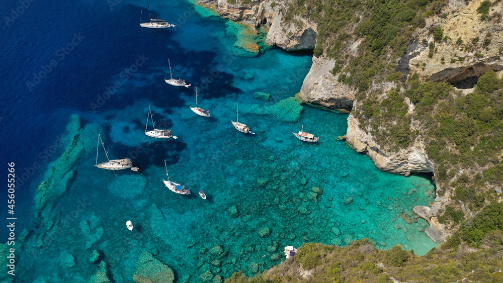 Aerial drone photo of sail boats anchored in tropical Caribbean island paradise bay with white rock caves and turquoise clear sea