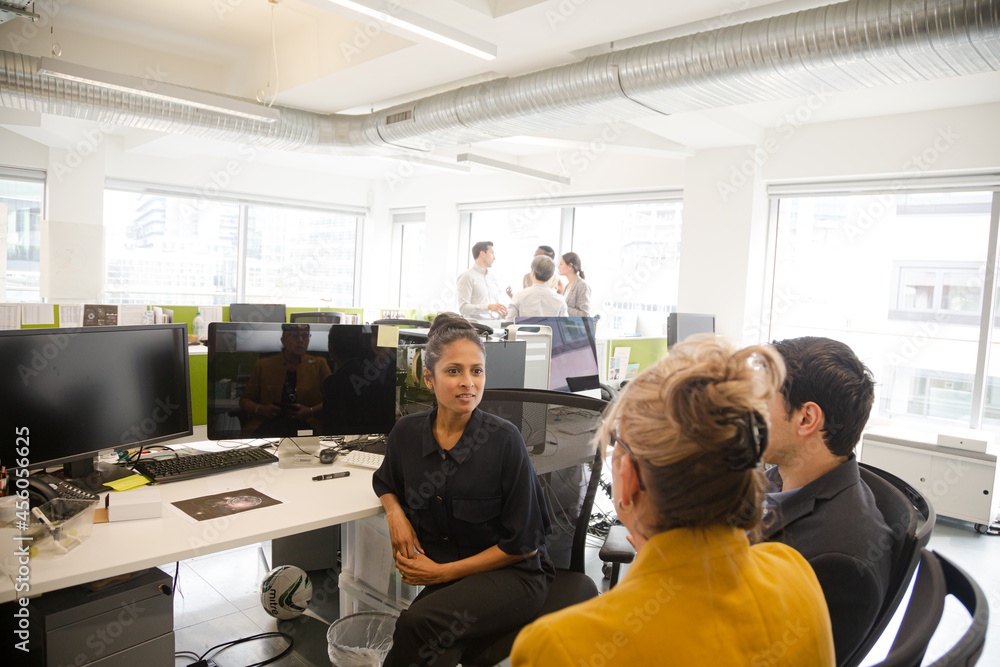 Business people talking in open plan office Business people talking in open plan office