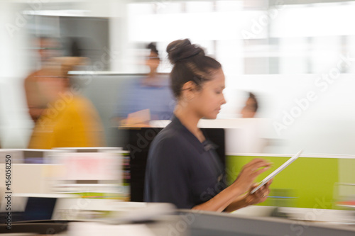 Photos Businesswoman using tablet computer in open plan office