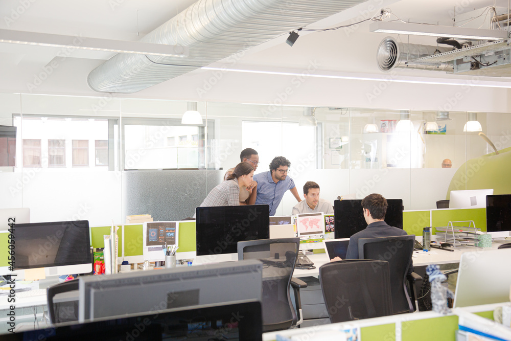 Business people brainstorming at computer in open plan office