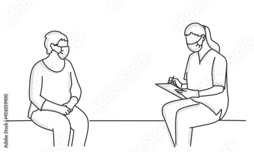 Patient and doctor in protection mask sit opposite each other, keeping a distance.