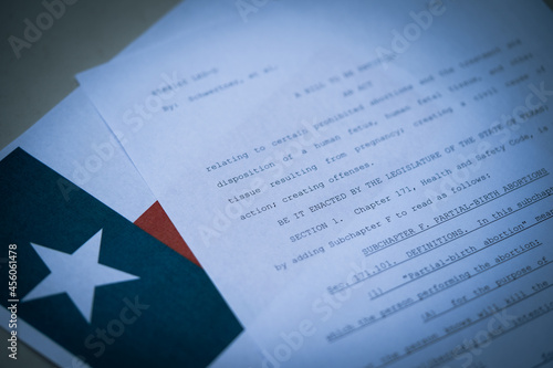 Blurred Close up view of Texas Abortion Law (TX SB8) next to the flag of Texas state.