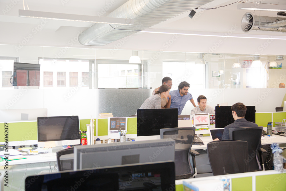 Business people brainstorming at computer in open plan office