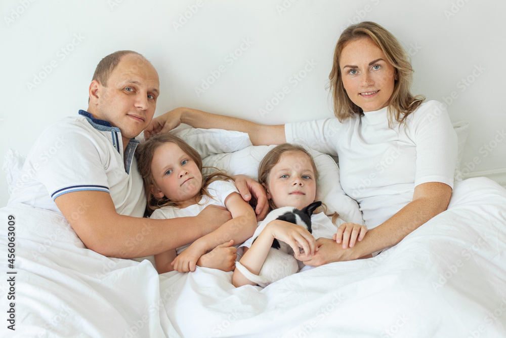 Family relaxing on sofa in bedroom. Little girls children, mother, father