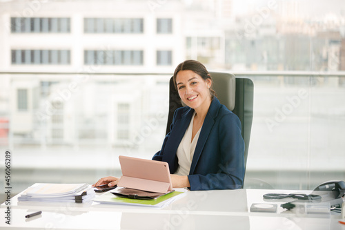 Businesswoman using smartphone and tablet computer at desk