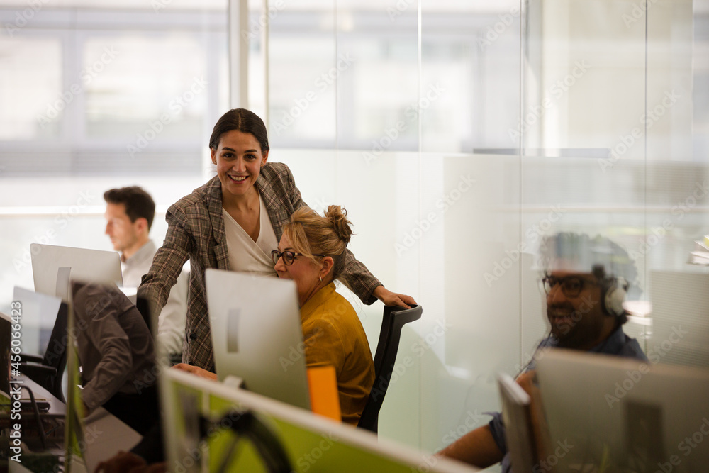 Business people talking at computer in open plan office