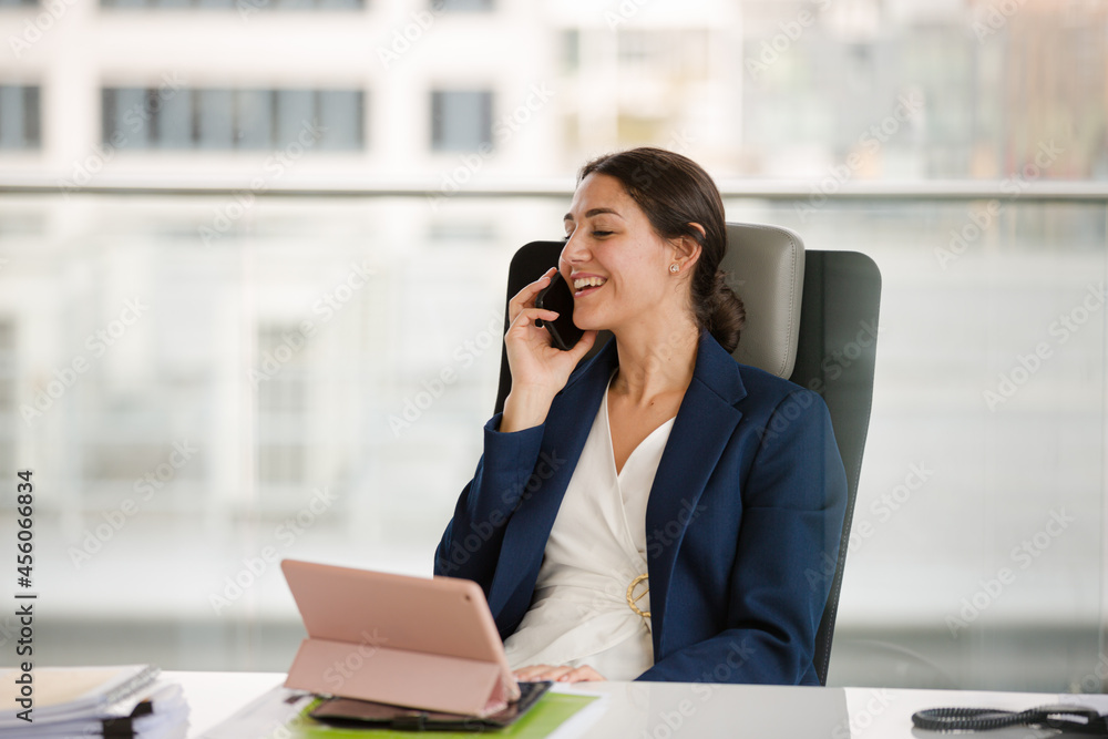 Businesswoman talking on cell phone and using tablet computer at desk Businesswoman talking on cell phone and using tablet computer at desk