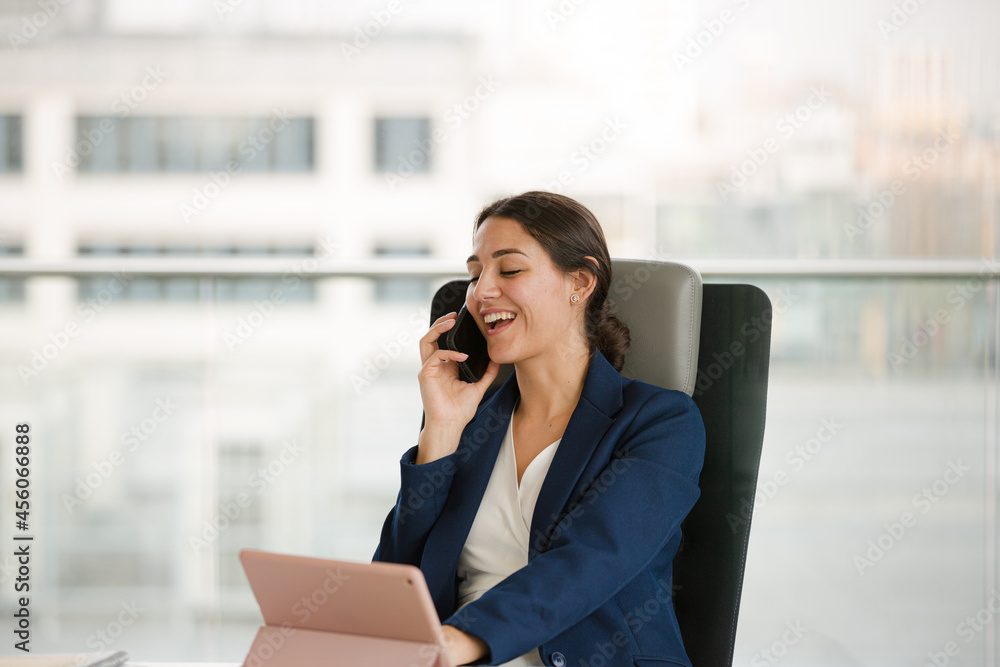 Businesswoman talking on cell phone and using tablet computer at desk Businesswoman talking on cell phone and using tablet computer at desk