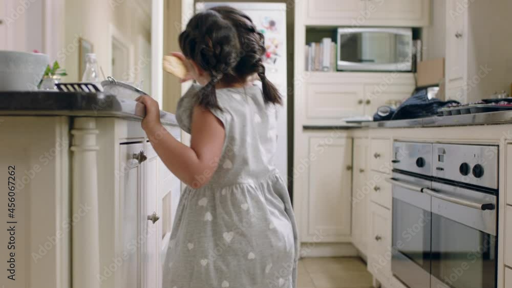 happy little girl taking cookie sneaky child stealing biscuit in kitchen at home happy little girl taking cookie sneaky child stealing biscuit in kitchen at home