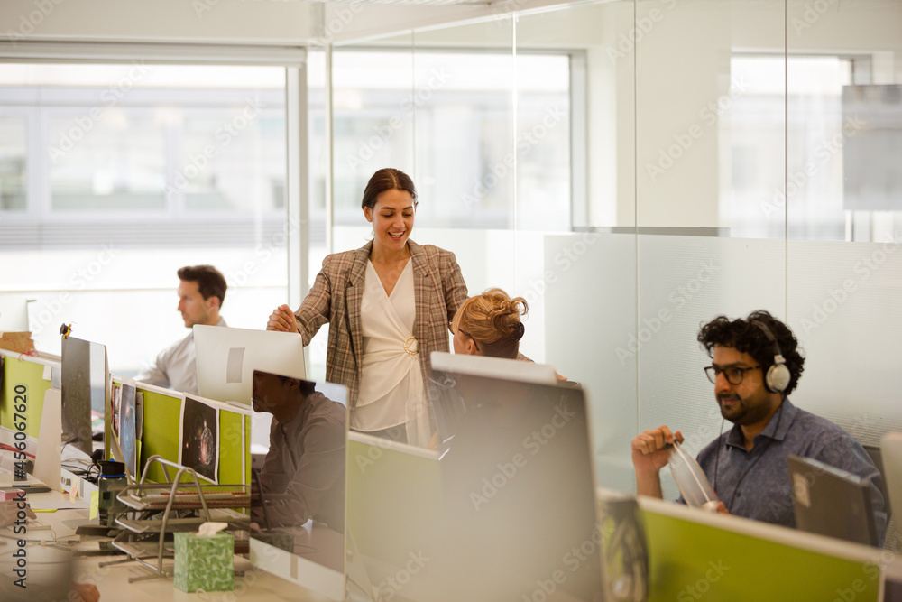 Business people talking at computer in open plan office