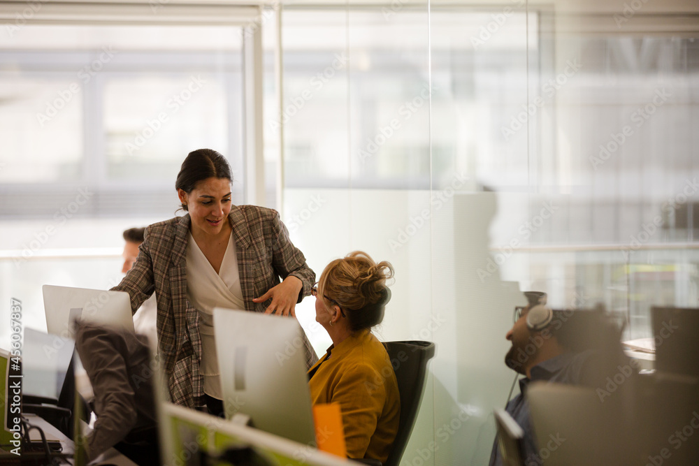 Business people talking at computer in open plan office Business people talking at computer in open plan office