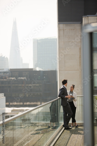 Businessman and businesswoman enjoying coffee on balcony, talking