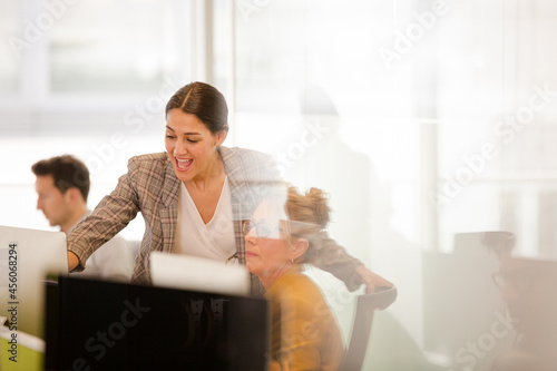 Businesswomen talking at computer in open plan office
