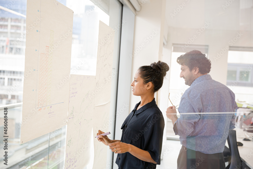 Fototapeta premium Business people discussing diagram sketches hanging on office window