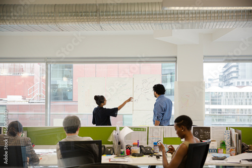 Business people discussing diagram sketches hanging on office window