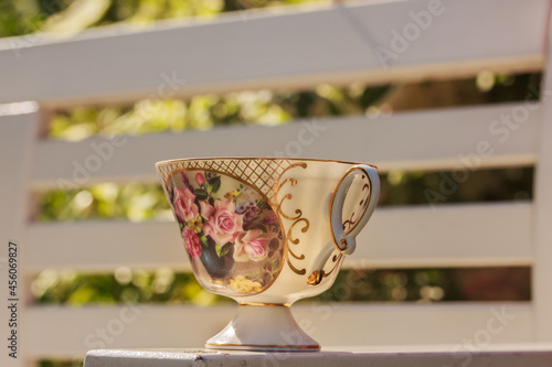 Floral teacup on white wooden background in the garden on a sunny day. Outdoor tea drinking , stock photo, copy space © Anna