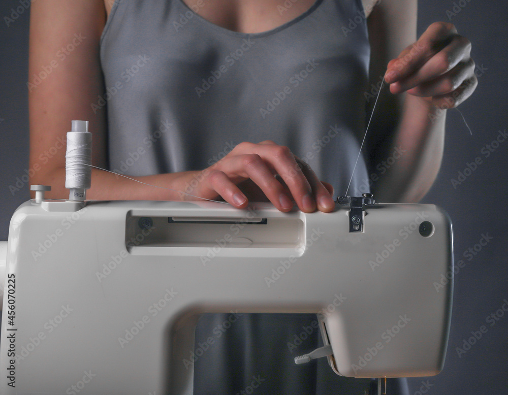 Naklejka premium Seamstress hands putting thread on sewing machine, work process.
