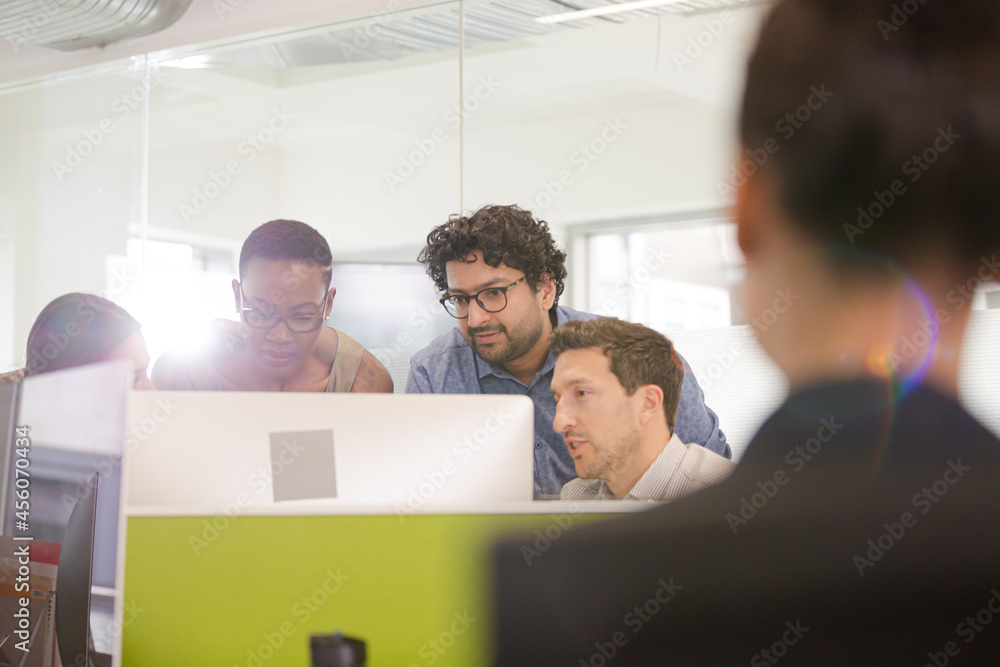 Business people brainstorming at computer in open plan office