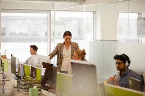 Business people talking at computer in open plan office