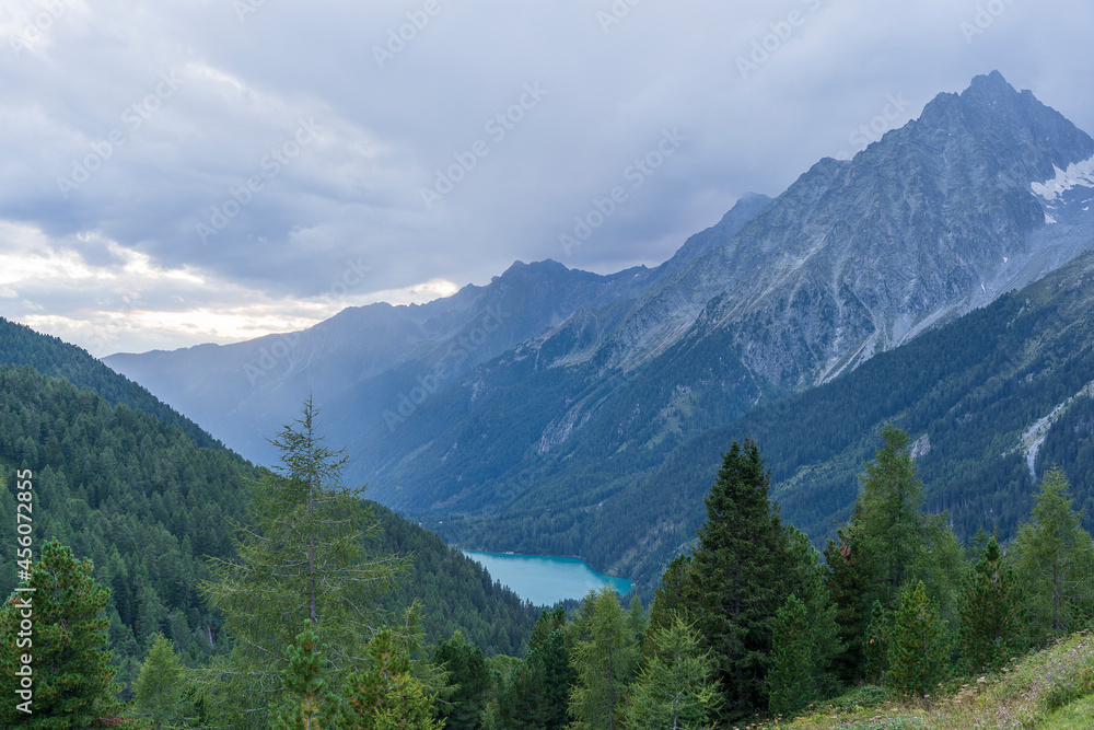 Landscape of Hochgall mountain peaks covered by clouds, valley and Antholzer See lake in Dolomites, Italy