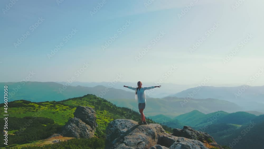Happy woman standing on a big stone. Beautiful landscape of the Ukrainian Carpathians. Morning in the mountains. Female tourist spins around standing Happy woman standing on a big stone. Beautiful landscape of the Ukrainian Carpathians. Morning in the mountains. Female tourist spins around standing