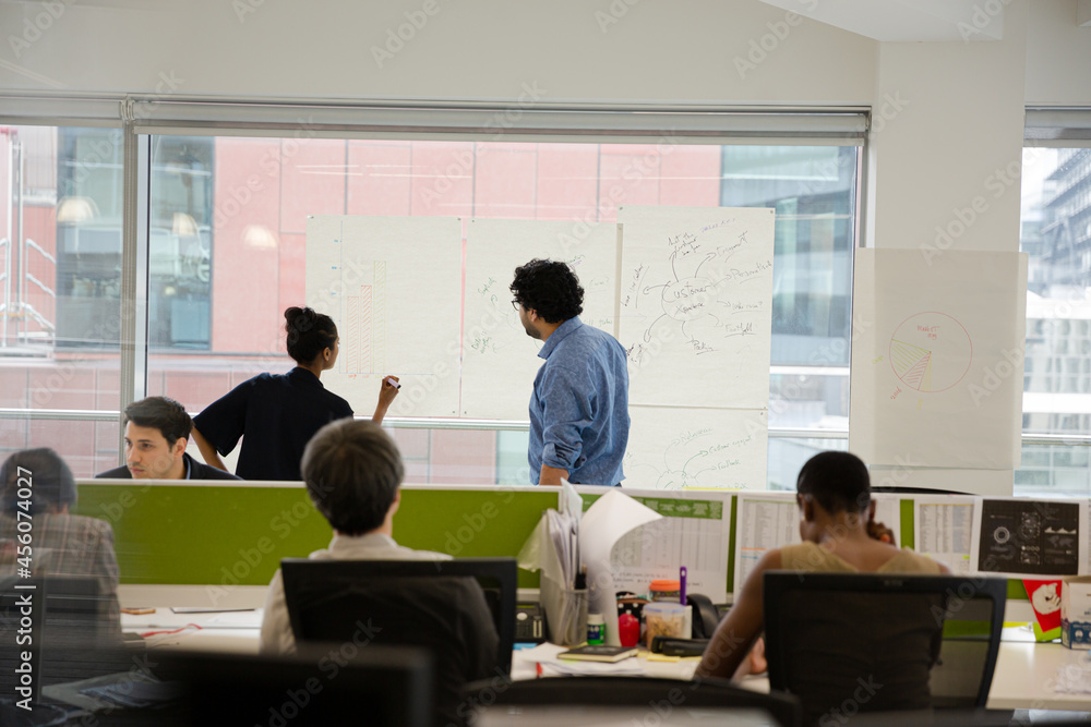 Fototapeta premium Business people discussing diagram sketches hanging on office window