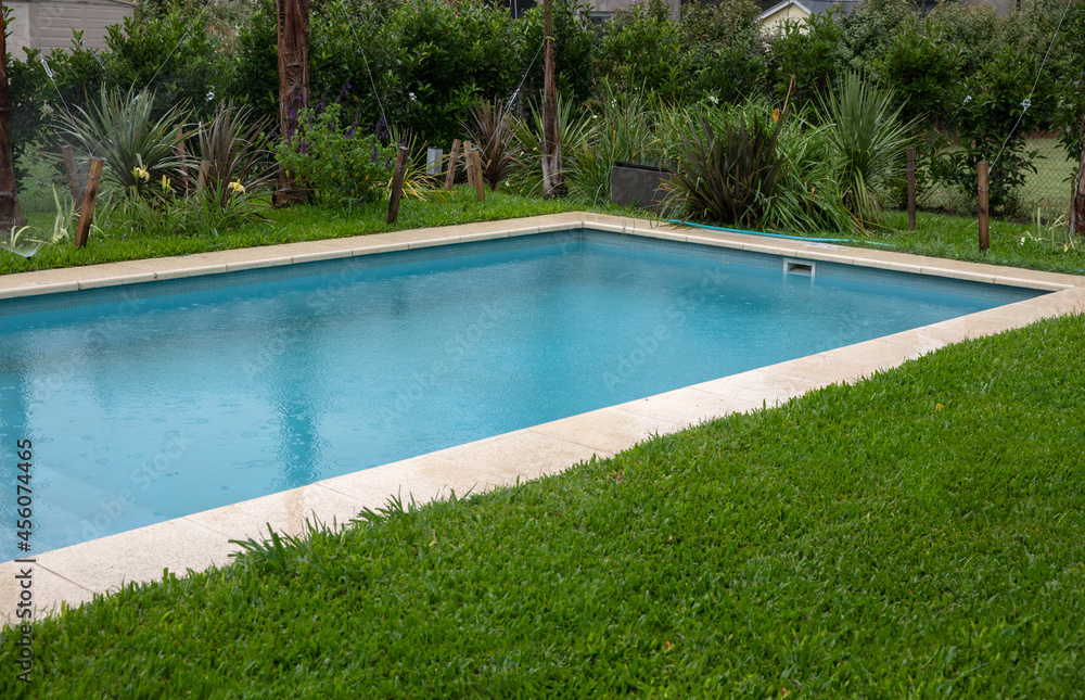 The house rectangular swimming pool and green grass in the backyard. 