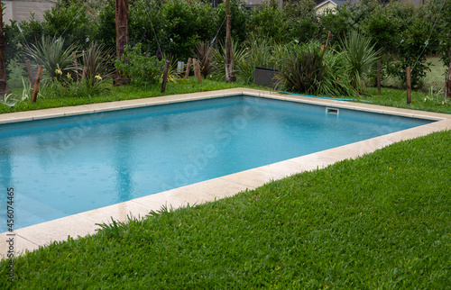 The house rectangular swimming pool and green grass in the backyard. 