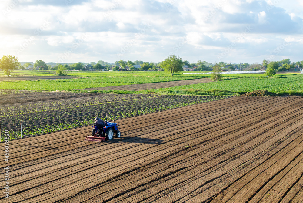 A farmer on a tractor cultivates a field. Land cultivation. Seasonal worker. Recruiting and hiring employees for work in a farm. Farming, agriculture. Preparatory earthworks before planting a new crop A farmer on a tractor cultivates a field. Land cultivation. Seasonal worker. Recruiting and hiring employees for work in a farm. Farming, agriculture. Preparatory earthworks before planting a new crop