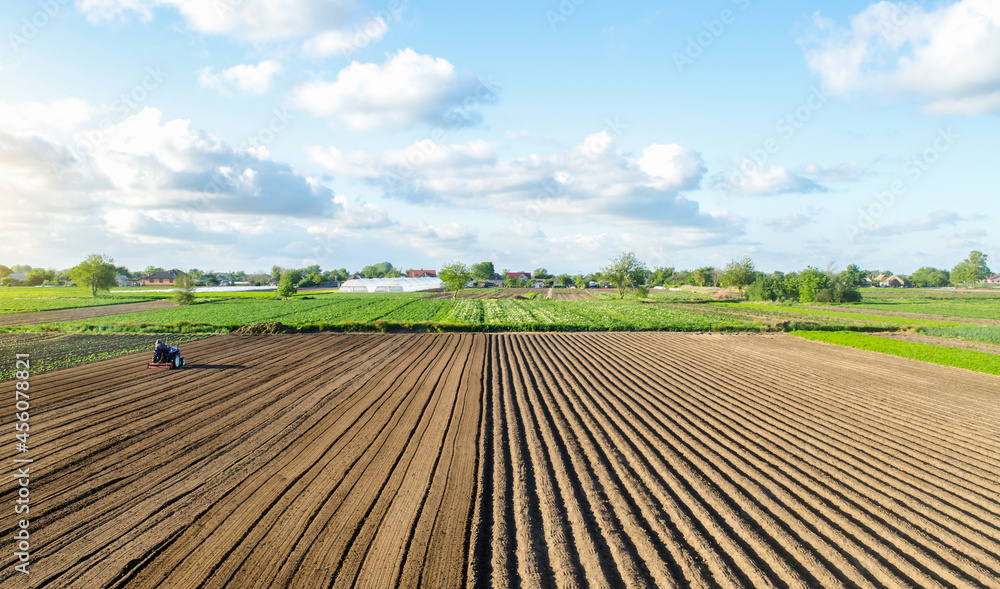 Farm field landscape and a tractor. Agricultural industry. Development of agricultural economy. Farming, agriculture. Loosening surface, land cultivation. Preparing for a new planting. Cutting rows