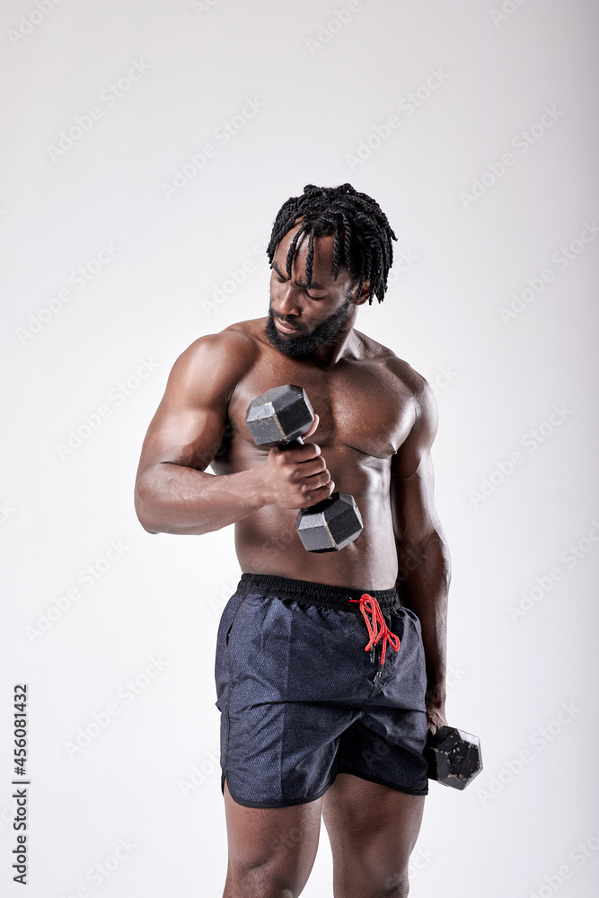 very strong young guy bodybuilder of african appearance doing exercises with dumbbells isolated on white background. Fitness athlete male with muscular body. Sports and fitness. portrait very strong young guy bodybuilder of african appearance doing exercises with dumbbells isolated on white background. Fitness athlete male with muscular body. Sports and fitness. portrait