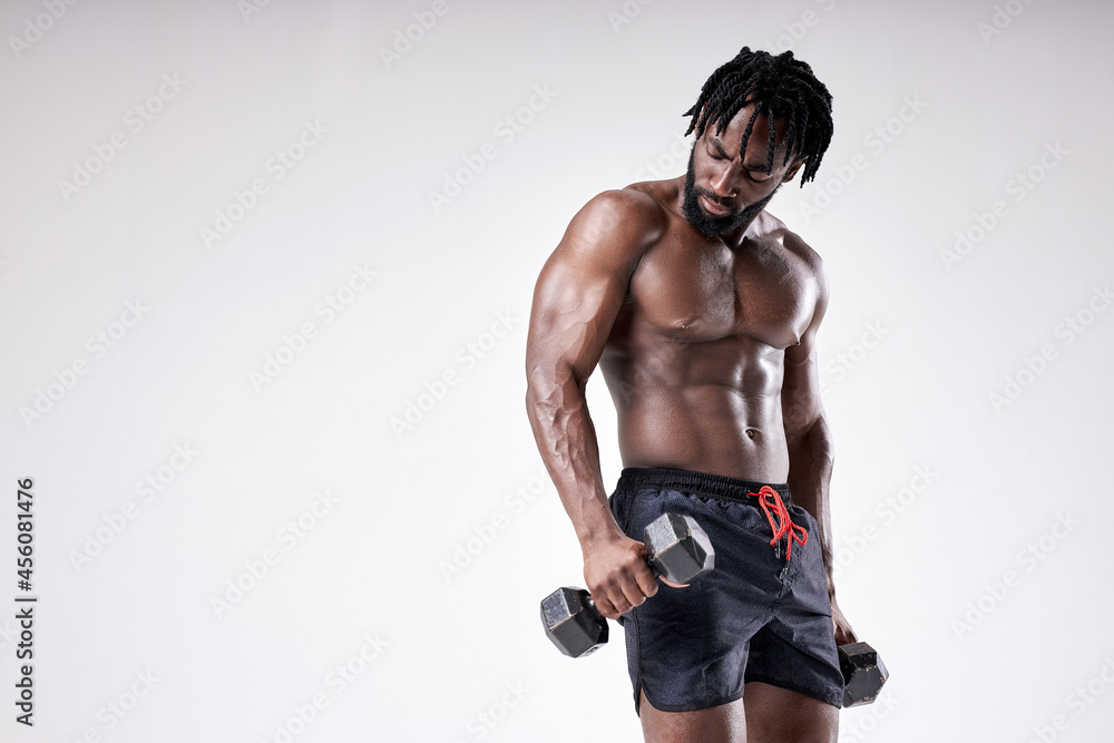 Masculine african guy with muscular sportive body holding dumbells on white background, posing. young athlete guy with dark skin in perfect physical shape, engaged in sport. portrait Masculine african guy with muscular sportive body holding dumbells on white background, posing. young athlete guy with dark skin in perfect physical shape, engaged in sport. portrait