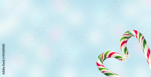 Christmas horizontal background with lollipops on a blue background with bokeh. Poster, banner, greeting card template. Festive background.