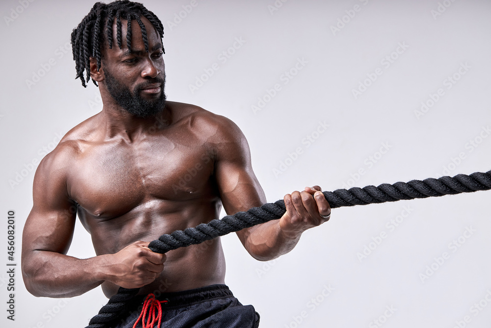 handsome young fit bearded afro sportsman pulling rope strongly ...