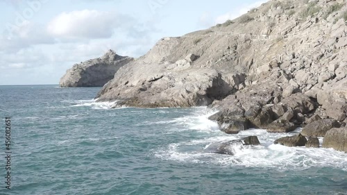 Water splashing. Pirate Bay Novy Svet Places. Crimea. Sea water beats against rocks. It consists of ancient coral reef colonies. Sea waves of blue-gray water beat against the coastal rocks.